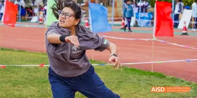 A student from Kunming No.1 High School International Education competes in a track and field event, captured mid-throw.