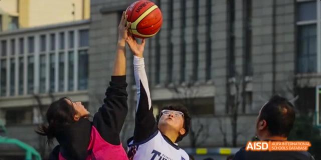 An action shot of a male student from Kunming No.1 High School International Education playing basketball and reaching for the ball during a game.