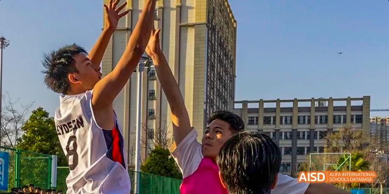 A student from Kunming No.1 High School International Education raises their fist in celebration, with a building in the background.
