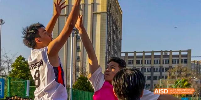 A student from Kunming No.1 High School International Education raises their fist in celebration, with a building in the background.