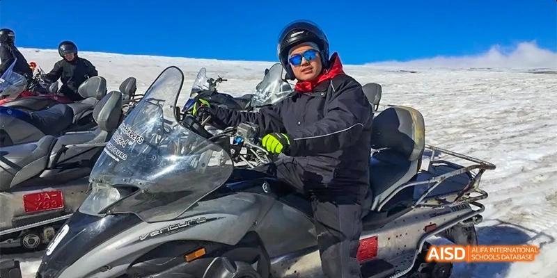A person from Kunming No.1 High School International Education in black motorcycle gear sits on a bike.