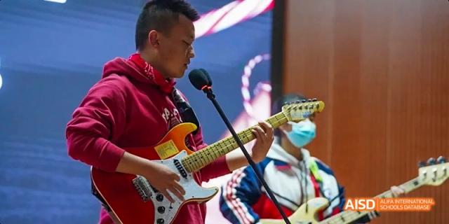 A student from Kunming No.1 High School International Education plays an electric guitar on a stage.