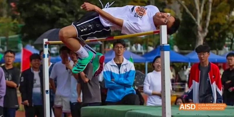 Two students from Kunming No.1 High School International Education are sitting and smiling at an outdoor event.