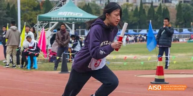 A female student from Kunming No.1 High School International Education runs with a baton during a relay race.