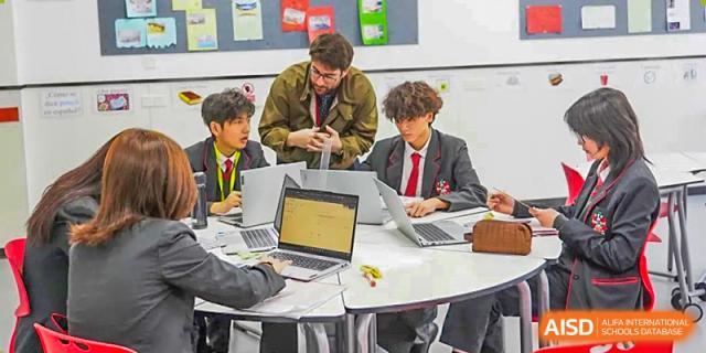 A group of male students from Lady Eleanor Holles International School Foshan (LEH Foshan) sit together, working on laptops for a project.