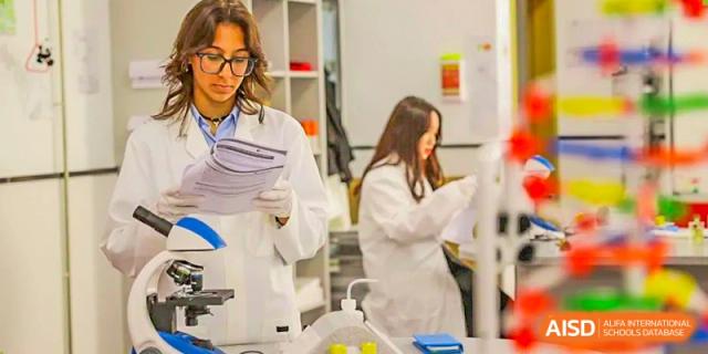 Two female students from Lady Eleanor Holles International School Foshan (LEH Foshan) in lab coats work on a science experiment.