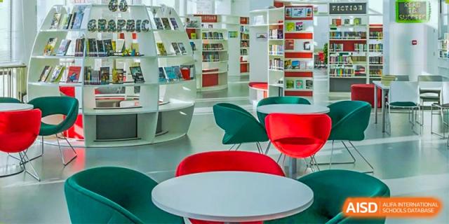 A brightly lit common area at Lady Eleanor Holles International School Foshan (LEH Foshan) with white tables and colorful green and red chairs.
