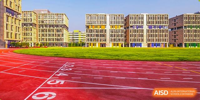 A sports track and field at Lady Eleanor Holles International School Foshan (LEH Foshan) with the main school building in the background.