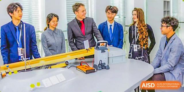 Two students from Lady Eleanor Holles International School Foshan (LEH Foshan) in school uniforms work with a teacher on a project.