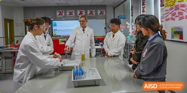 Two students from Lady Eleanor Holles International School Foshan (LEH Foshan) in lab coats work with beakers and test tubes in a science lab.