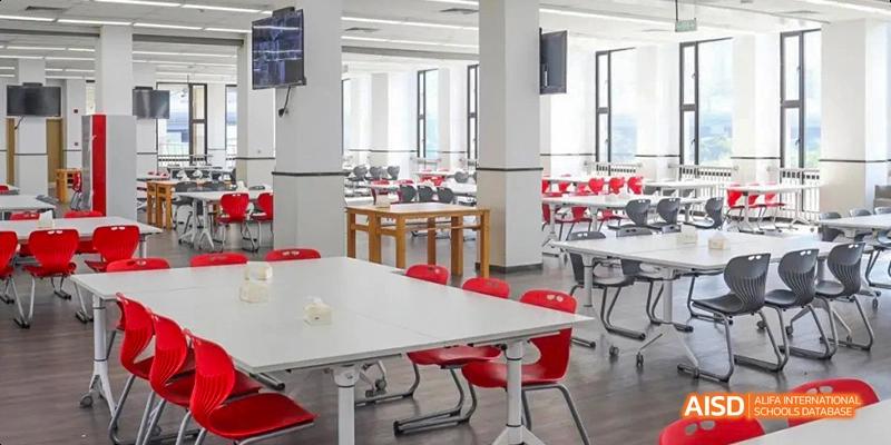 A bright and modern school canteen with white tables and red chairs at Lady Eleanor Holles International School Foshan(LEH Foshan).