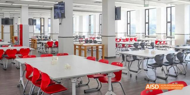 A bright and modern school canteen with white tables and red chairs at Lady Eleanor Holles International School Foshan(LEH Foshan).