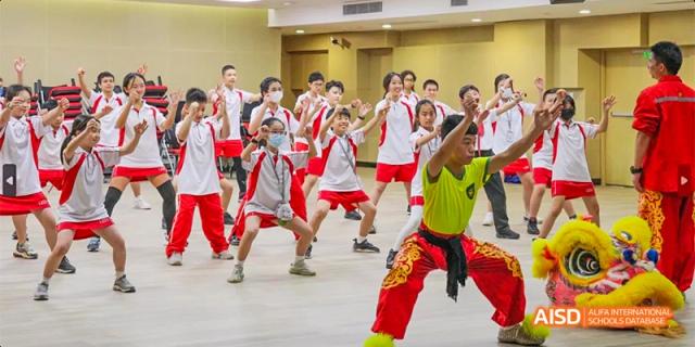 Students from Lady Eleanor Holles International School Foshan(LEH Foshan) in red and white uniforms practicing a traditional Chinese dance or martial art in a classroom.