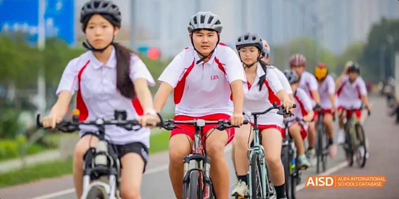 Students from Lady Eleanor Holles International School Foshan(LEH Foshan) wearing helmets and school uniforms riding bicycles.
