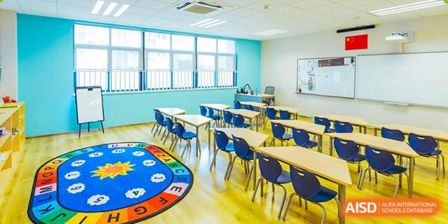 A colorful classroom for young students at Nord Anglia School Guangzhou Panyu with desks, chairs, and a round rug on the floor.