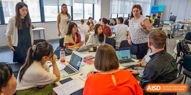 A group of students from Nord Anglia School Guangzhou Panyu collaborating on a project with laptops in a classroom setting.