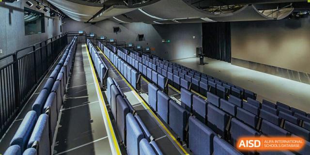 An empty auditorium with rows of blue seats at Nord Anglia School Guangzhou Panyu.
