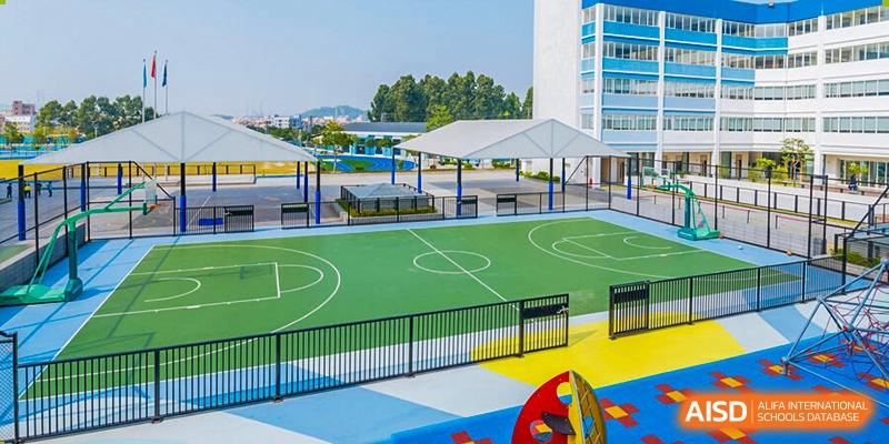 An outdoor sports court at Nord Anglia School Guangzhou Panyu with playground equipment and a covered seating area.