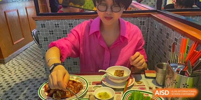 A person in a bright pink shirt preparing to eat a bowl of soup, an activity that could be part of a Nord Anglia School Guangzhou Panyu event.