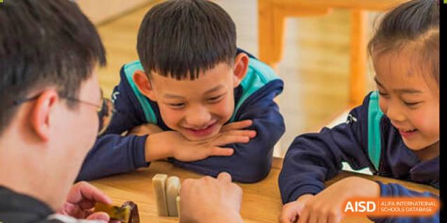 A smiling young student from Nord Anglia School Guangzhou Panyu with their chin resting on their hands.
