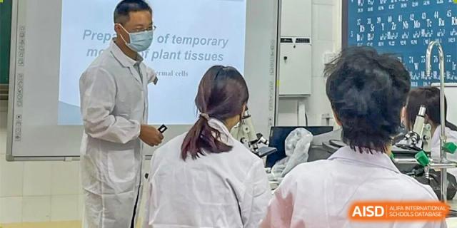 Students seated in a classroom facing a projector screen displaying a slide about "temporary plant tissues" at Orange County American High School Beijing Campus.