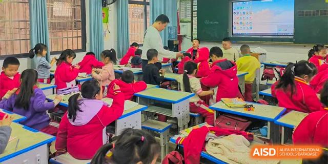 A teacher standing in front of a class of younger students in red jackets, teaching a lesson at Orange County American High School Beijing Campus.