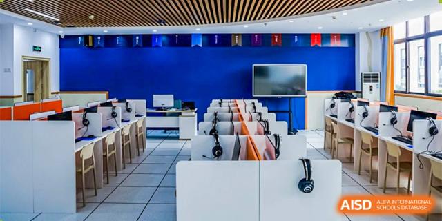 A modern language lab or multimedia room with blue walls, computers, and headphones at Orange County American High School Beijing Campus.