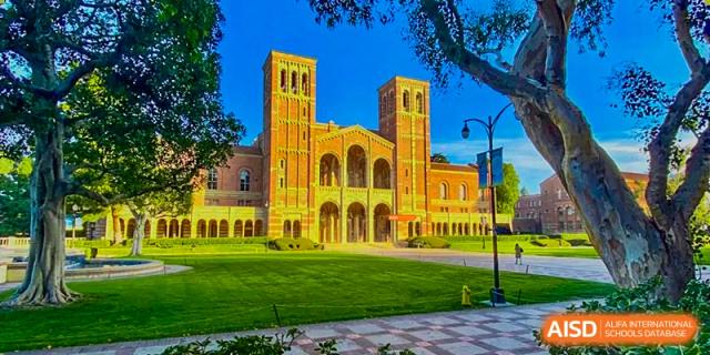 A vibrant, wide-angle photo of a grand, historic building with twin towers and a green lawn, representing a campus partnership or trip for Orange County American High School Beijing Campus.