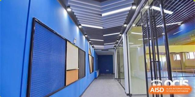 A modern hallway or corridor at Oriental Cambridge International School with bright blue walls and recessed lighting in the uniquely structured ceiling.