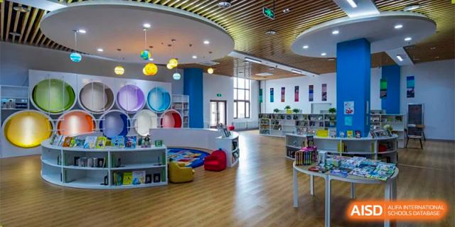 The colorful and open-plan school library or learning center at Oriental Cambridge International School, featuring bookshelves, reading nooks, and playful hanging decorations.