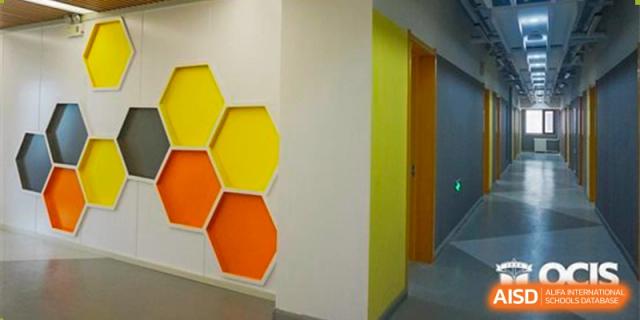 A brightly lit interior space at Oriental Cambridge International School featuring a yellow wall with decorative orange and yellow hexagonal panels.