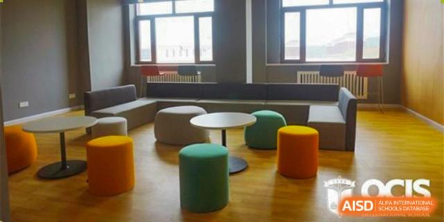 A cozy student common area at Oriental Cambridge International School with low seating, colorful round stools, and small circular tables.