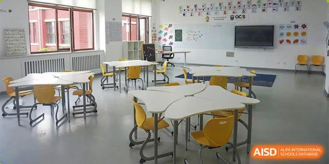 A standard classroom at Oriental Cambridge International School with whiteboards, bright lighting, and flexible white desks and yellow chairs.