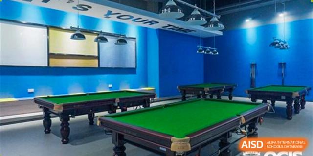 The bright blue and green billiards room at Oriental Cambridge International School, featuring two pool tables and modern lighting.