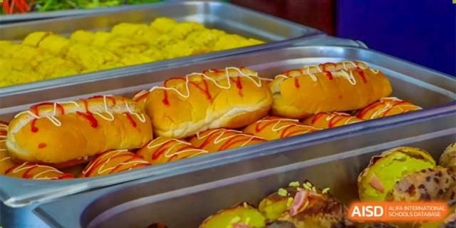 A close-up of a serving tray filled with baked goods and pastries, including glazed donuts, available to students at Oriental Cambridge International School.