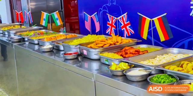 A food serving station at Oriental Cambridge International School displaying various items, including small flags of the United Kingdom and Malaysia as part of a cultural or international event.