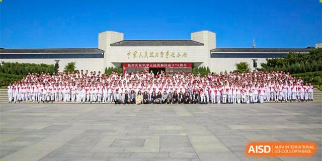 A group of students and teachers from RCF Experimental School posing for a group photo in front of the school building.