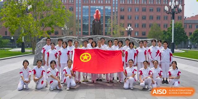 A large group of students from RCF Experimental School holding a red banner with a yellow star for a group photo.