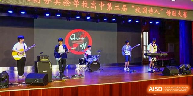 Students from RCF Experimental School performing in a band on a brightly lit stage during a school event.