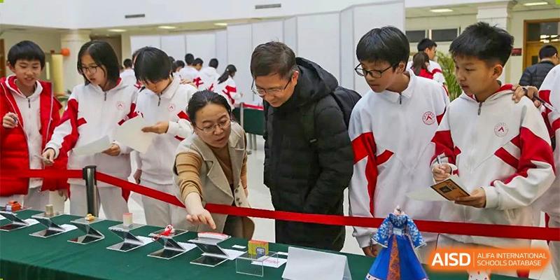 Students and an adult from RCF Experimental School standing at a table, looking at various electronic devices during an exhibition.