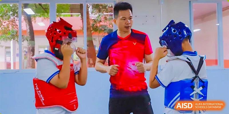 An instructor in a vibrant red athletic shirt guides students through a martial arts drill in a bright studio at Guangzhou Yinghao School.