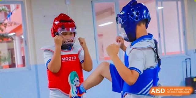 Two young students in red and blue protective gear practice martial arts kicks during a training session at Guangzhou Yinghao School.