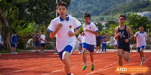 Two students in white polos compete in a sprinting race on a red running track during a school sports day at Guangzhou Yinghao School.