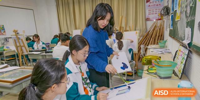 A female teacher assisting a group of students with an activity or project in a classroom at Guangdong Experimental High School IFPAD & A-Level.