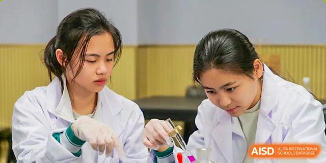 Students conducting a science experiment, holding glassware and liquids in a lab setting at Guangdong Experimental High School IFPAD & A-Level.