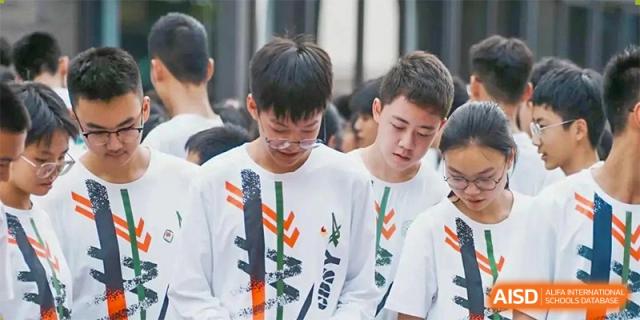 A close-up of male students in white t-shirts standing together in a group outdoors at Guangdong Experimental High School IFPAD & A-Level.