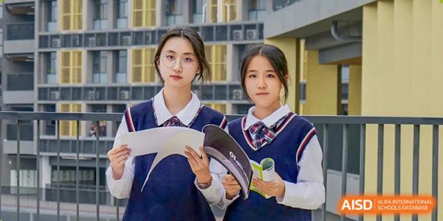 Two female students in school uniform reviewing papers and notes together at Guangdong Experimental High School IFPAD & A-Level.