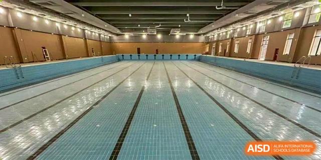 Interior view of a large, empty indoor swimming pool with multiple lanes at Guangdong Experimental High School IFPAD & A-Level.