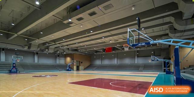 Interior view of a large, well-equipped indoor gymnasium with a basketball court at Guangdong Experimental High School IFPAD & A-Level.