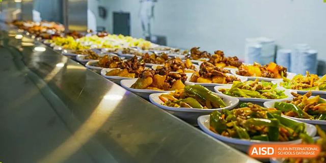 A buffet line showing trays of various prepared savory dishes, including meat and vegetables, available at the dining hall of Guangdong Experimental High School IFPAD & A-Level.